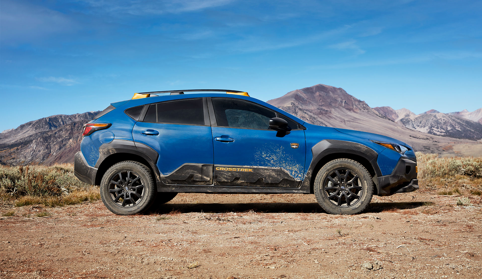 Side shot of 2025 Crosstrek Wilderness parked on dusty trail.