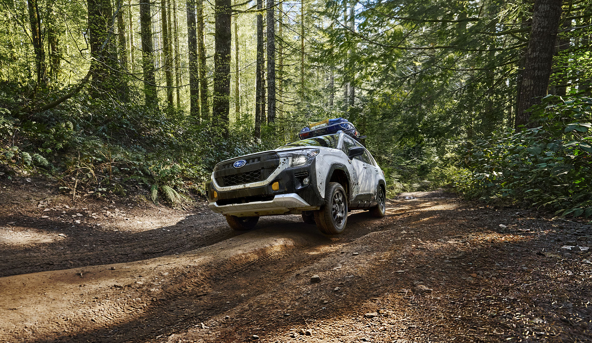 Low shot of the 2026 Subaru Forester Wilderness splashing through a wet and muddy trail.